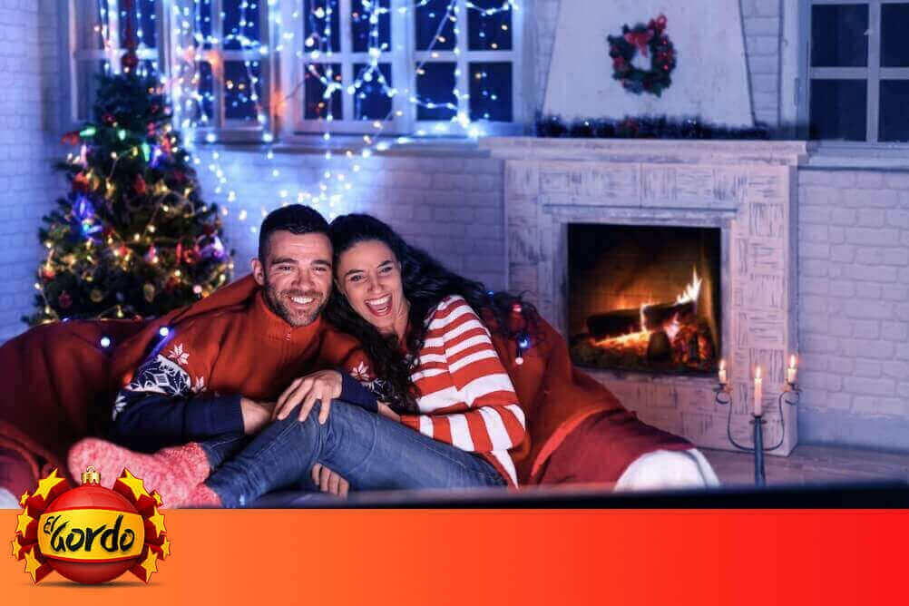 El Gordo Werbung Paar sitzt im weihnachtlichen Wohnzimmer und guckt Fernsehen