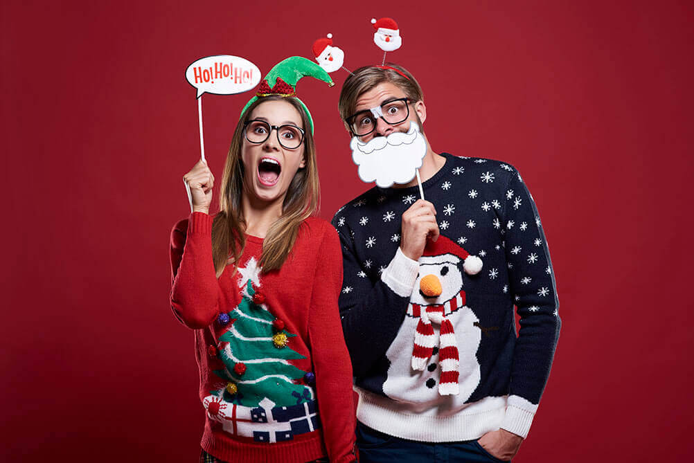 Ein Mann und eine Frau in lustigen Weihnachtspullovern 
