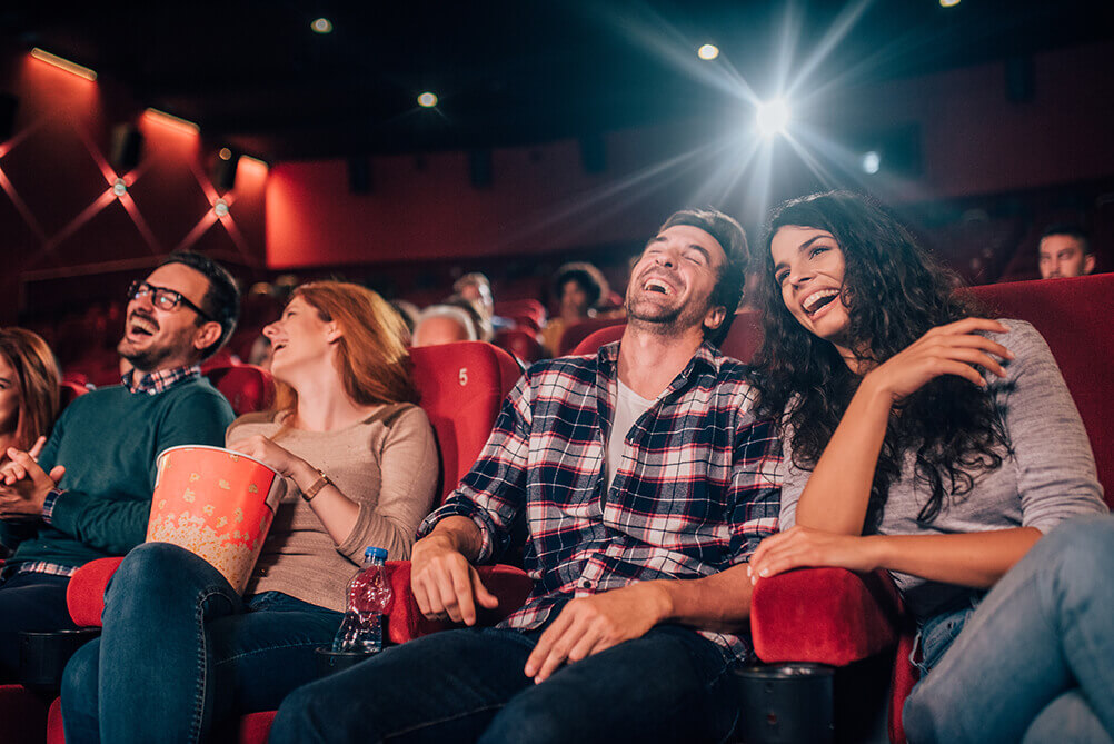 Kinobesucher schauen sich lachend einen Hollywood-Film an