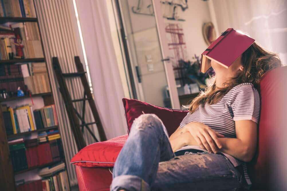 Frau sitzt auf dem Sofa mit einem Buch auf dem Gesicht