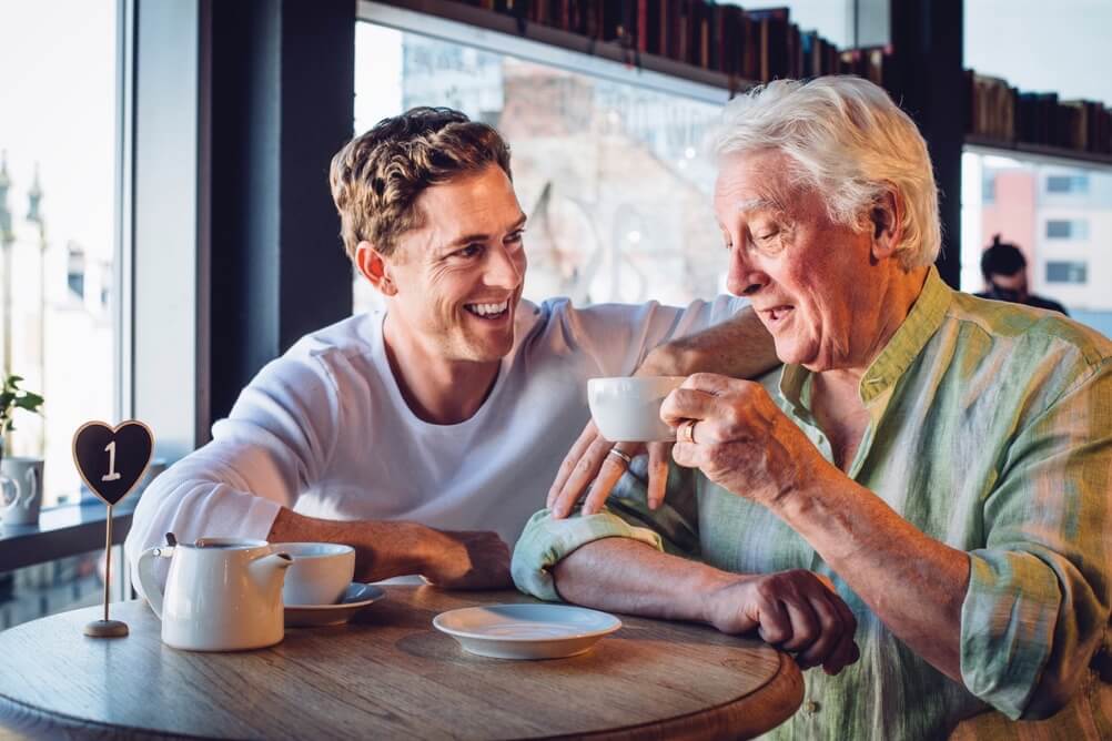 Sohn trinkt lachend mit seinem Vater Kaffee in einem Café am Vatertag