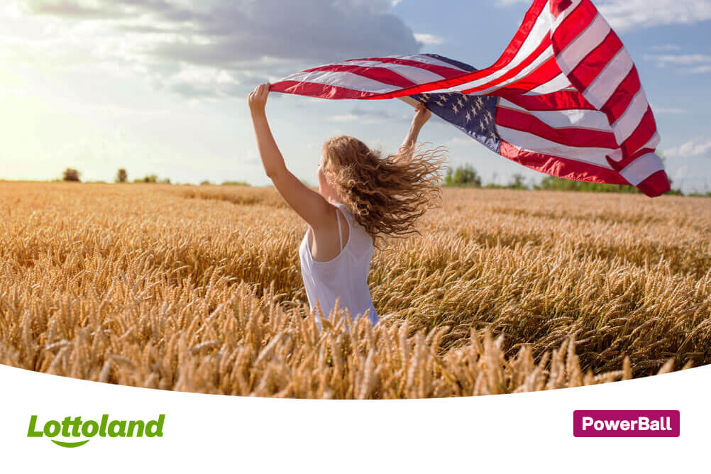 Junge Frau rennt mit einer amerikanischen Flagge durch ein Kornfeld