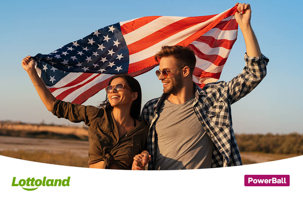 Glückliches Paar feiert einen PowerBall-Gewinn im Lottoland und hält gemeinsam eine große amerikanische Flagge